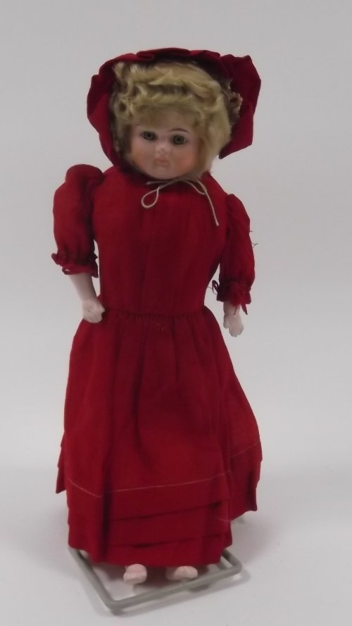 Appraisal: A composition doll with painted fixed eyes wearing a red