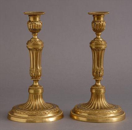 Appraisal: PAIR OF LOUIS XVI-STYLE GILT-METAL CANDLESTICKS Each leaf-banded fluted stem