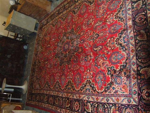 Appraisal: A Persian wine ground rug with central floral designs and