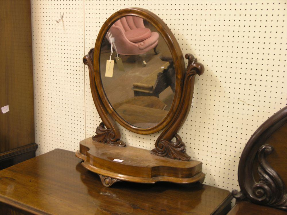 Appraisal: A Victorian mahogany toilet mirror oval mirror hinged upon carved