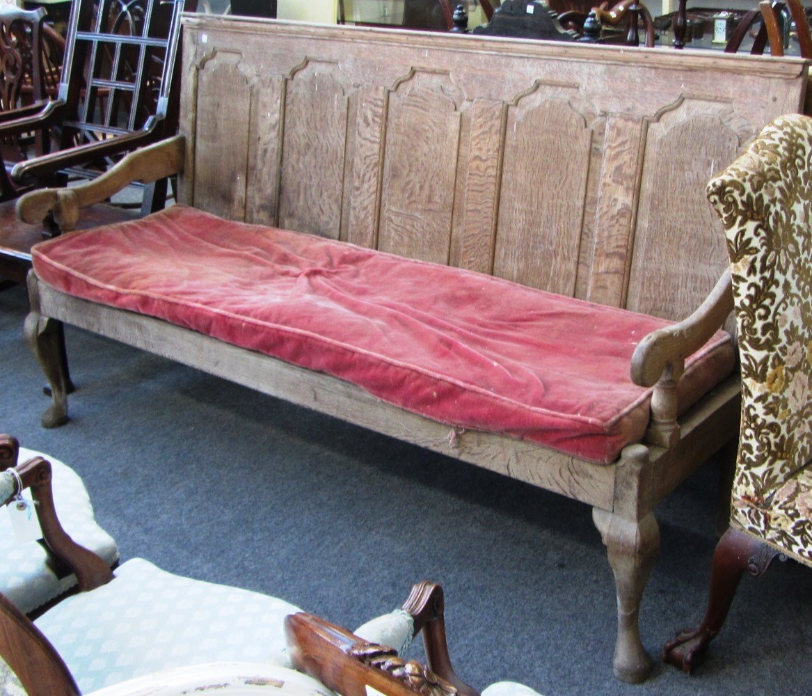 Appraisal: A George III oak arched panel backed open arm settle