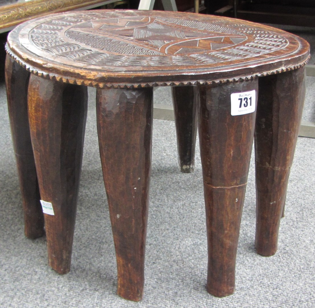 Appraisal: An African carved circular hardwood stool on ten tapering supports