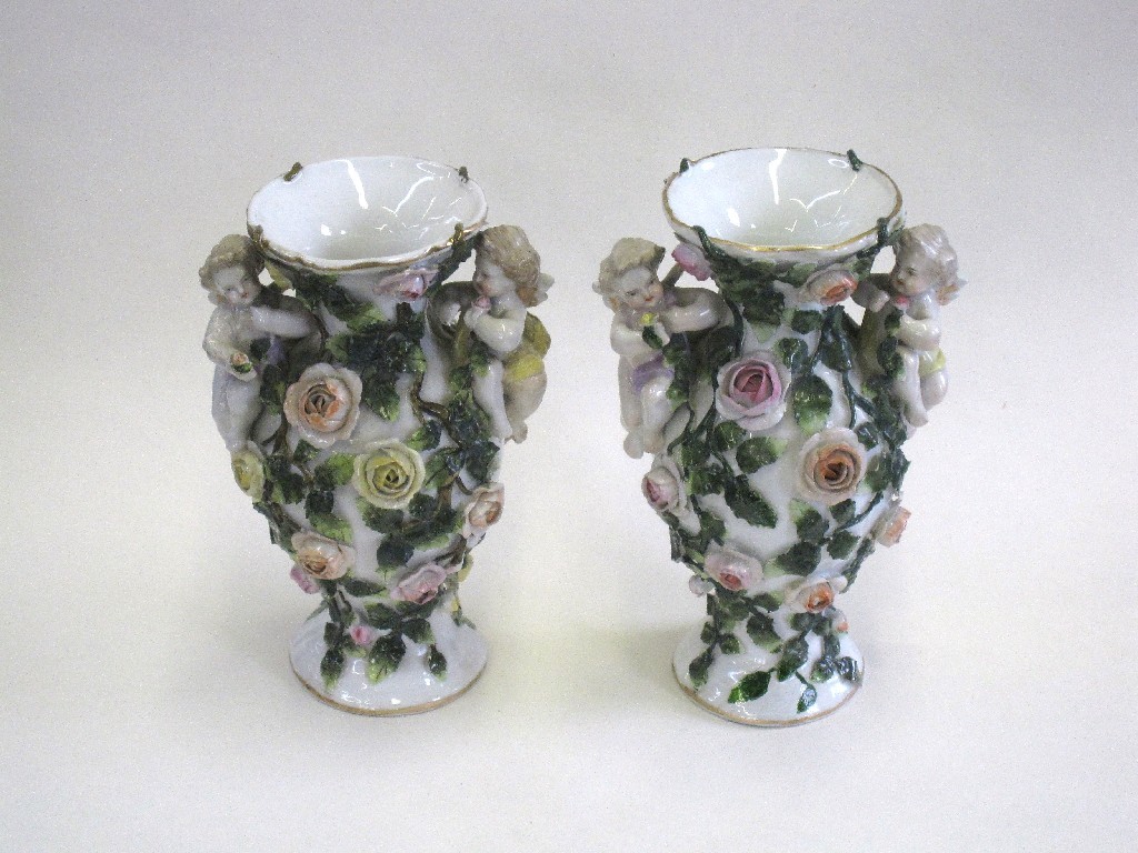 Appraisal: Pair of German floral encrusted vases each with two cherubs