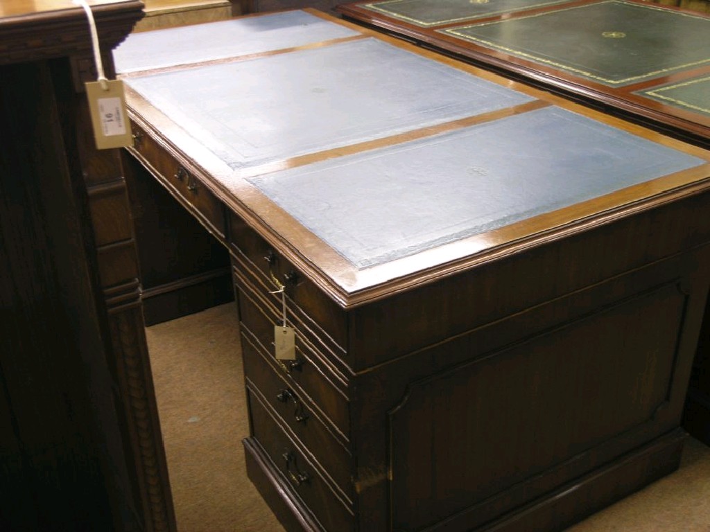 Appraisal: A reproduction mahogany veneered desk inset tooled blue leather top