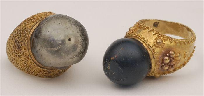 Appraisal: TWO GLASS BEAD RINGS in a crenelated gold mount the