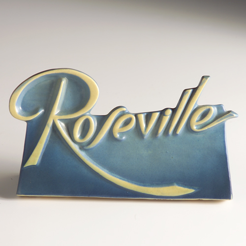 Appraisal: ROSEVILLE Dealer's sign with ivory scrolled letters on a blue