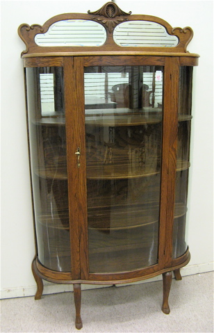 Appraisal: AN OAK AND CURVED GLASS CHINA CABINET American c having