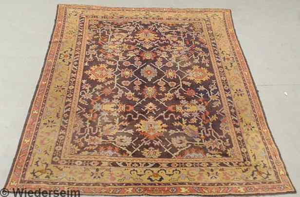 Appraisal: Oriental carpet aubergine field and overall floral patterns ' x