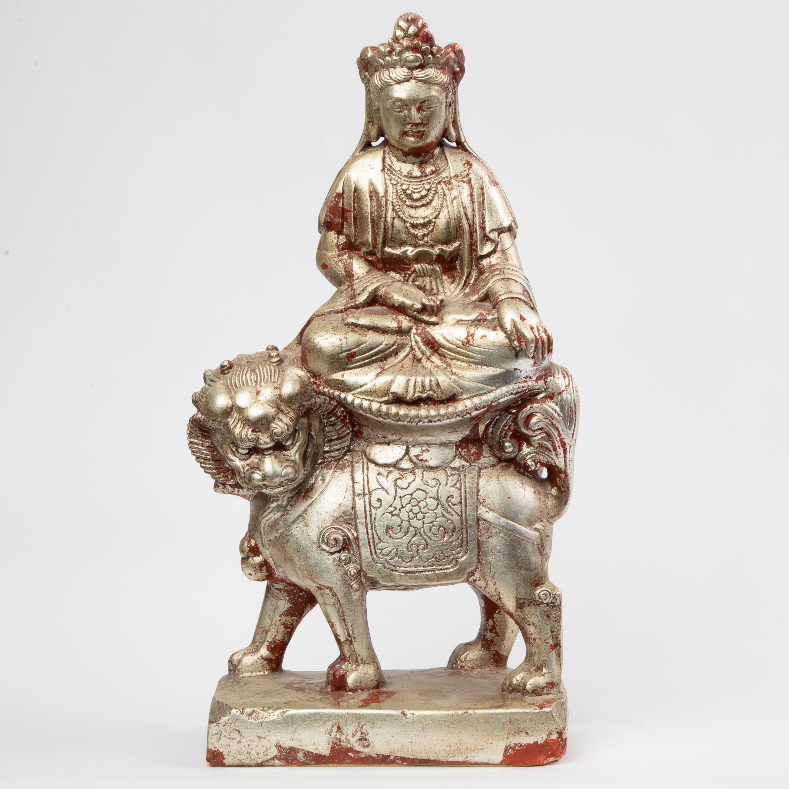 Appraisal: SILVER-LEAF GUANYIN ON BUDDHIST LION A ceramic Guanyin Kwan-Yin seated