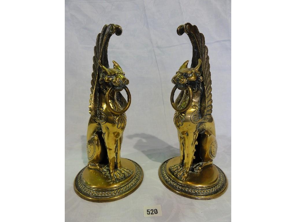 Appraisal: A pair of brass Griffin fire dogs