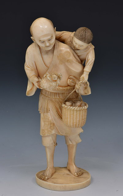 Appraisal: A Japanese ivory okimono of a standing fisherman and his