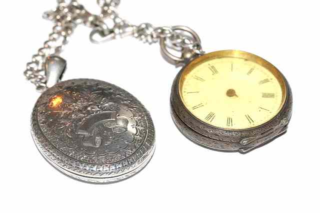 Appraisal: AN OVAL SILVER LOCKET engraved with flowers with silver chain