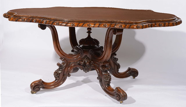 Appraisal: A Victorian walnut shaped centre tablewith carved border on swept