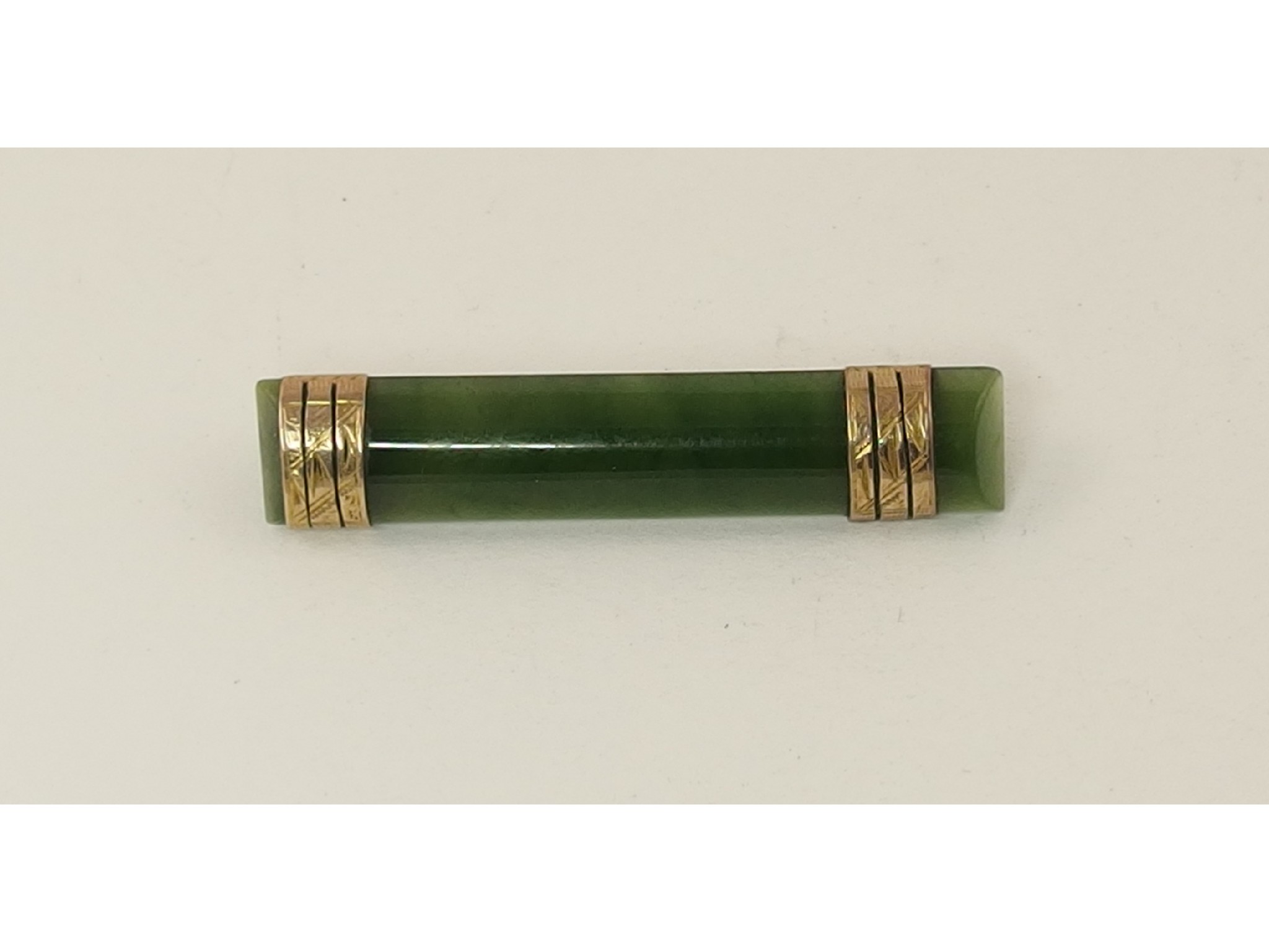 Appraisal: A New Zealand green hardstone bar brooch with ct gold