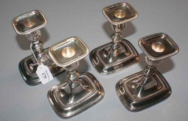 Appraisal: A SET OF FOUR SILVER PLATED CANDLESTICKS on rectangular bases