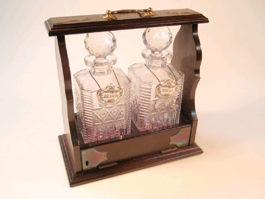 Appraisal: A mahogany Tantalus with two square cut decanters and faceted