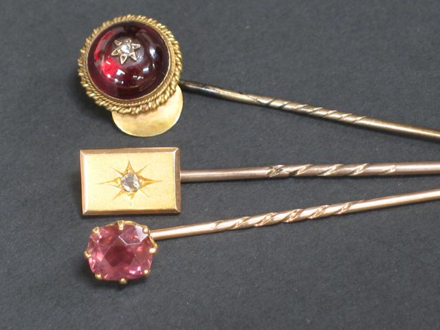 Appraisal: THREE STICK PINS including a circular carbuncle garnet and diamond