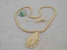 Appraisal: An ivory bead necklace with carved ivory pendant together with