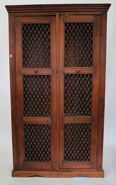 Appraisal: AN INDIAN HARDWOOD CUPBOARD with wrought iron lattice twin doors