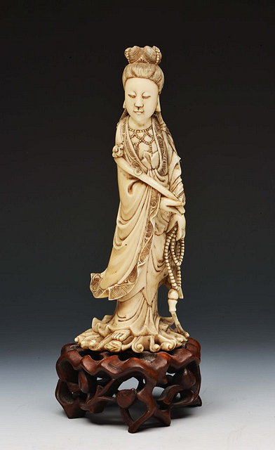 Appraisal: A CHINESE IVORY FIGURE OF QUANYIN holding a rui and