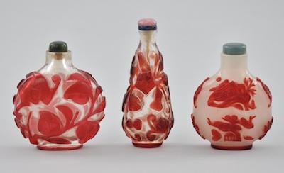 Appraisal: Three Peking Glass Carved Snuff Bottles in Red Three glass