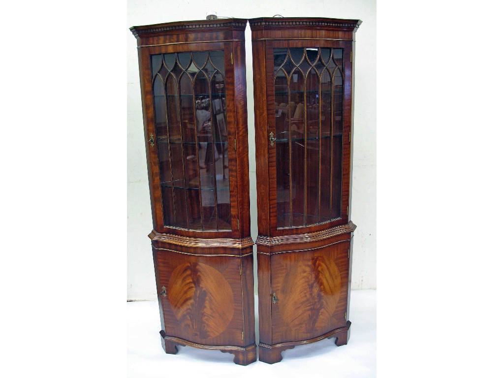 Appraisal: A pair of reproduction mahogany serpentine fronted corner cupboards -