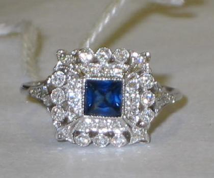 Appraisal: A DIAMOND AND SAPPHIRE RING comprising square cut sapphire surrounded