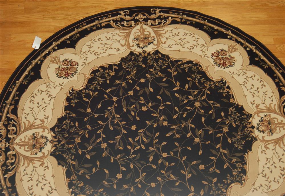 Appraisal: ROUND AUBUSSON SYNTHETIC RUG having a black field with a