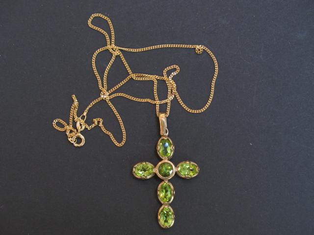 Appraisal: A PERIDOT CROSS PENDANT set with five oval cushion-cut peridot