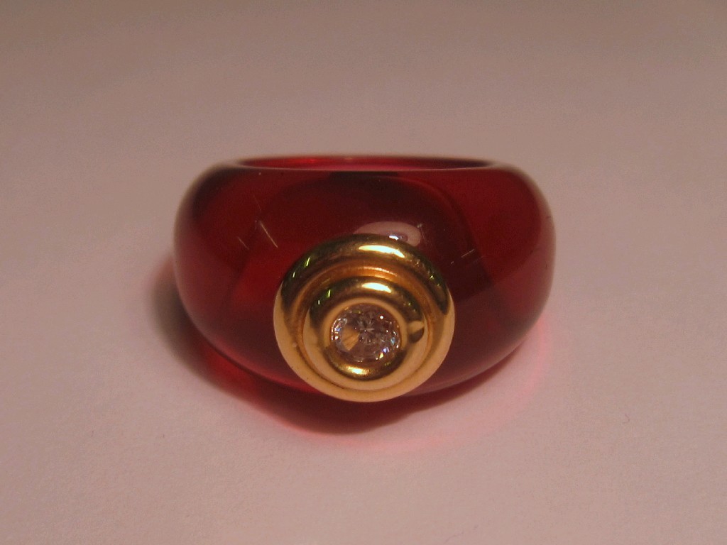 Appraisal: Red resin ring with collet set gold mounted stone inset