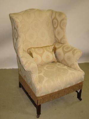 Appraisal: A MAHOGANY FRAMED WING ARM CHAIR upholstered in cream and