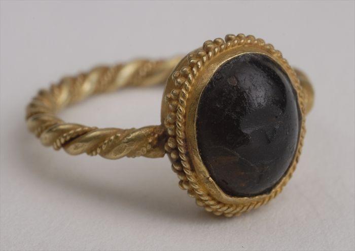 Appraisal: SMALL CABOCHON STONE IN A TWISTED AND CRENELATED GOLD MOUNT