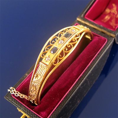 Appraisal: An Edwardian gold hinged bangle set with two sapphires and