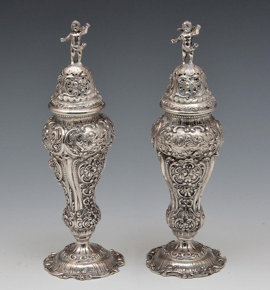 Appraisal: Pair of cast German silver repousse salt peppers with putti