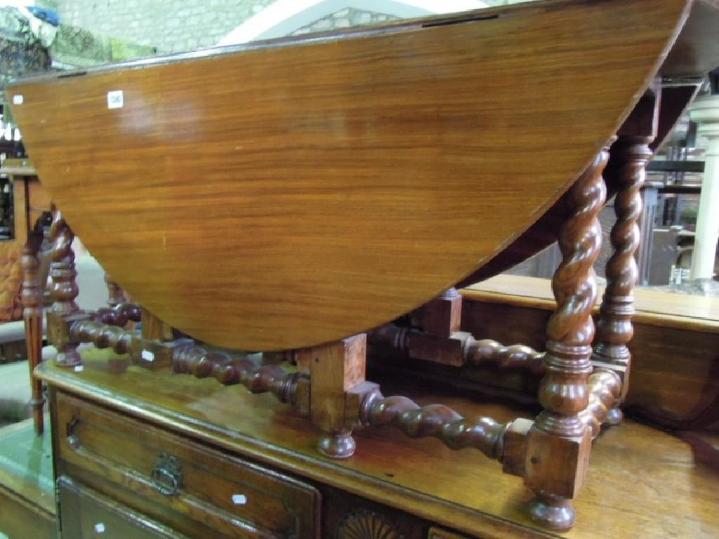 Appraisal: A walnut oval drop leaf gateleg low centre occasional table