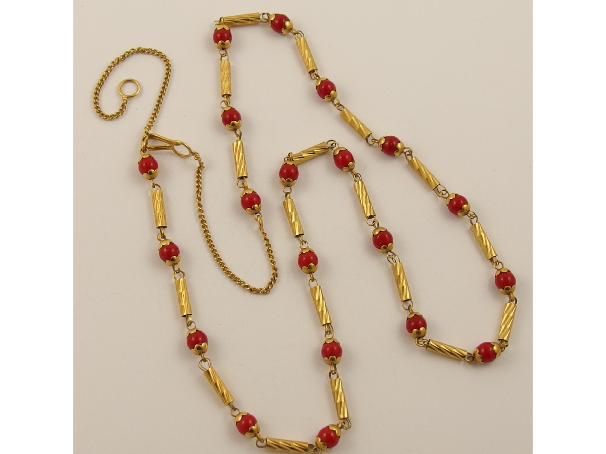 Appraisal: A bright yellow metal chain strung with red glass beads