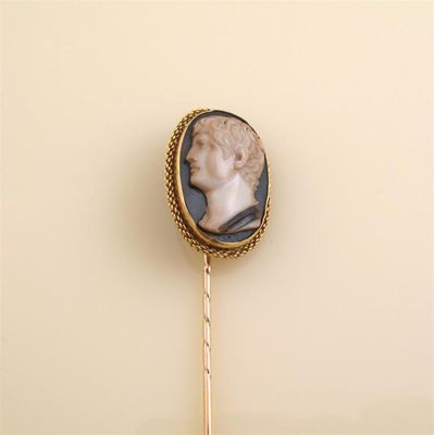 Appraisal: A gold stick pin mounted with a carved hard stone