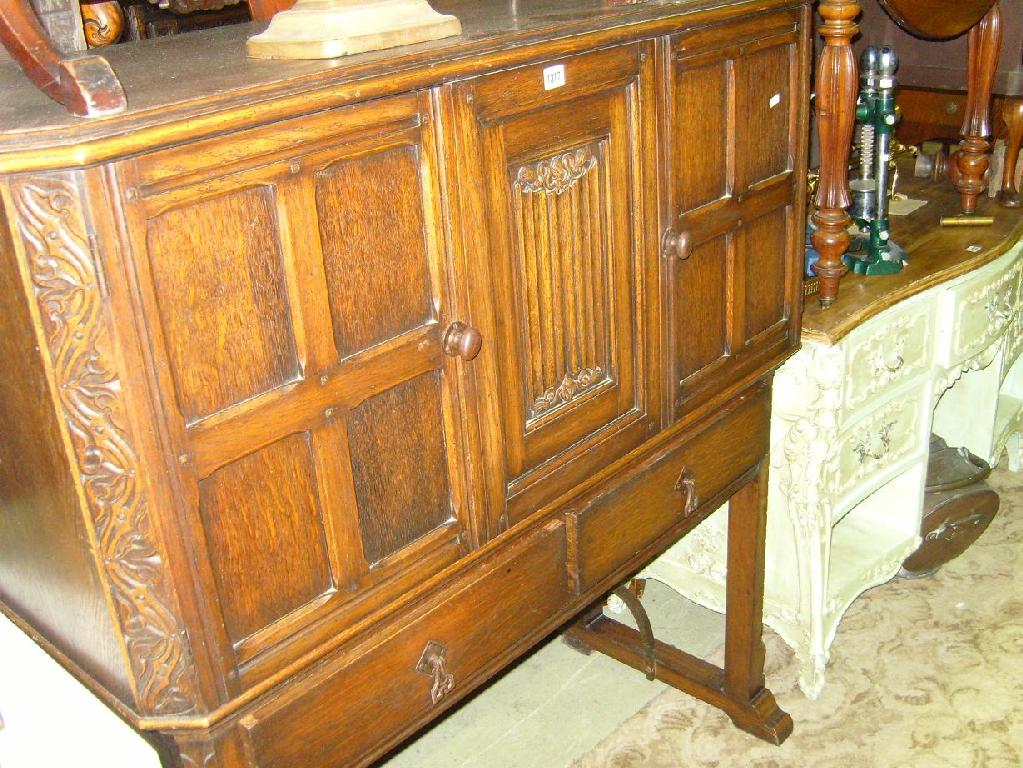 Appraisal: An oak cocktail cabinet enclosed by panelled doors above frieze