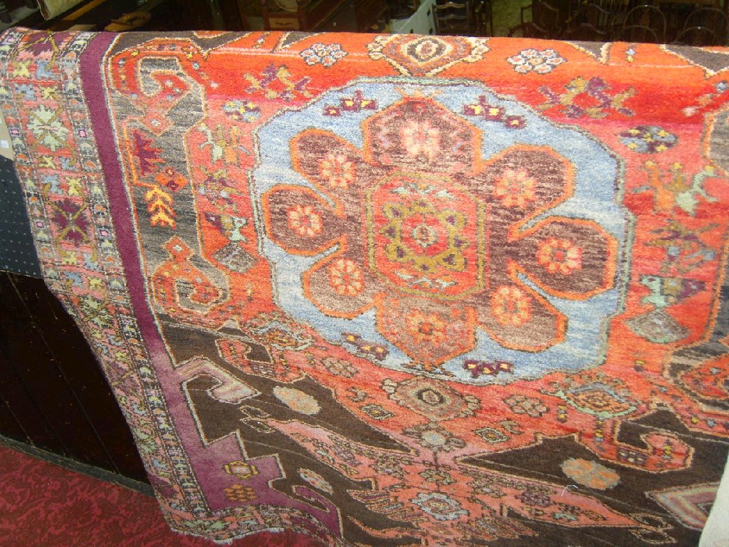 Appraisal: A Persian rug twin medallion centre upon a bright red