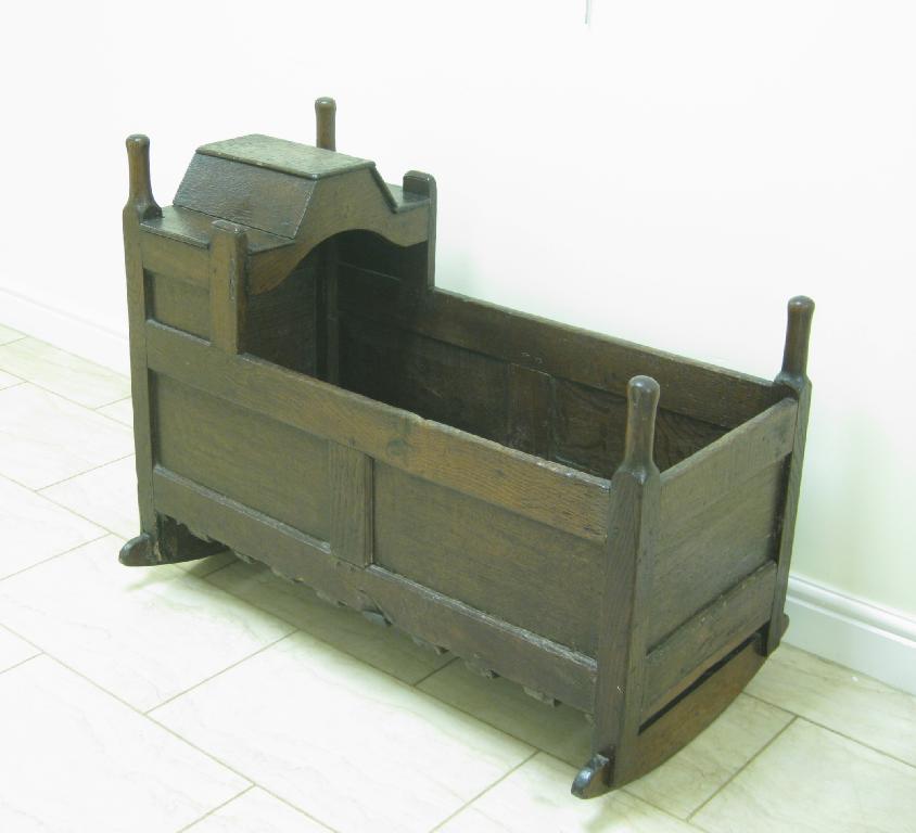 Appraisal: An antique oak Cradle with panelled sides and shaped hood