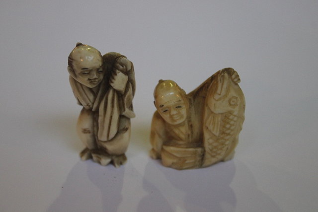 Appraisal: TWO JAPANESE IVORY NETSUKES man with sack and man with