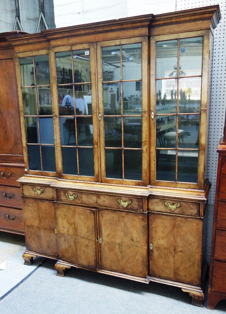 Appraisal: An th century style walnut breakfront bookcase cupboard the four