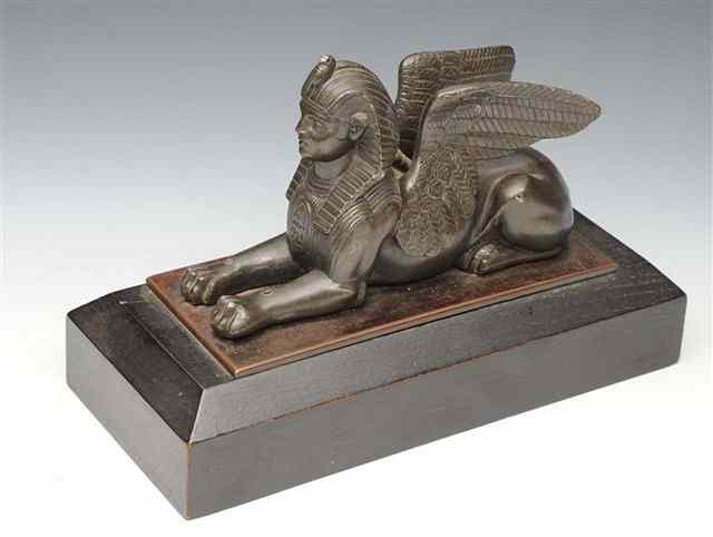 Appraisal: AN EGYPTIAN REVIVAL PATINATED BRONZE SPHINX on a rectangular wooden