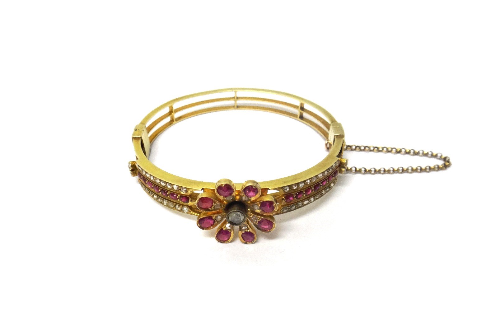 Appraisal: A gold ruby and diamond set oval hinged bangle the