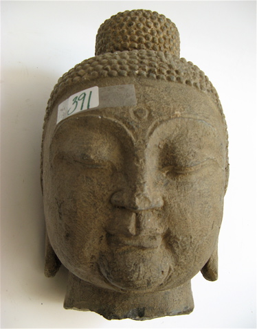 Appraisal: A GRANITE SCULPTED HEAD OF GAUTAMA BUDDHA having down cast