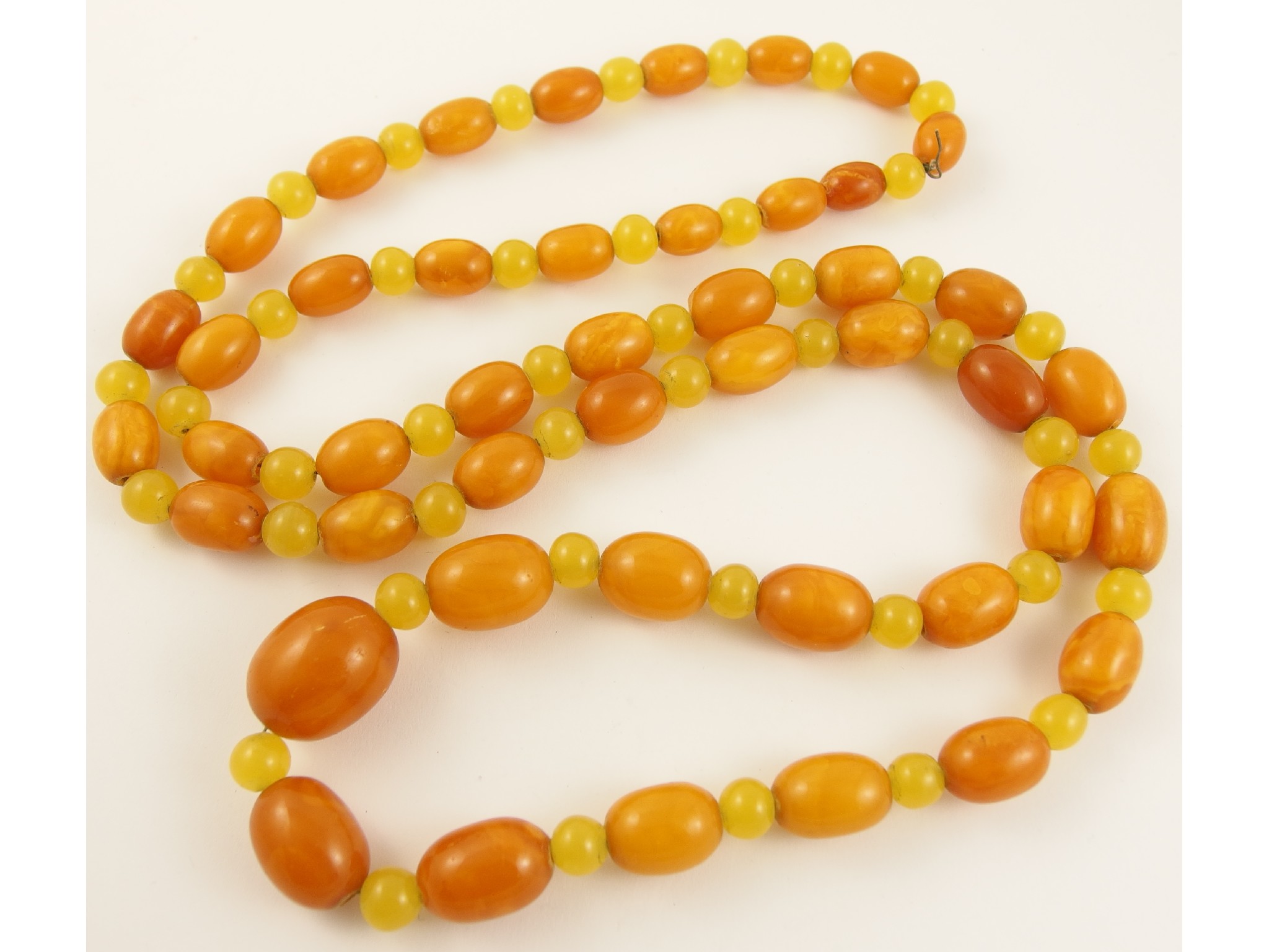 Appraisal: A string of yellow amber coloured beadsinterspaced with yellow glass