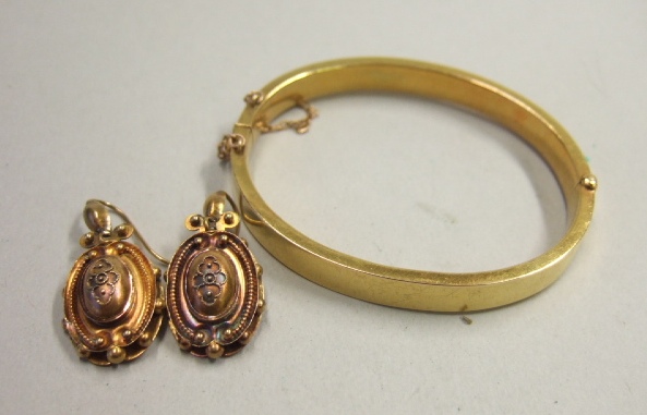 Appraisal: An oval gold hinged bangle on a snap clasp detailed