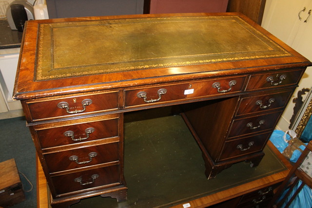 Appraisal: A REPRODUCTION MAHOGANY KNEE HOLE PEDESTAL DESK fitted with nine