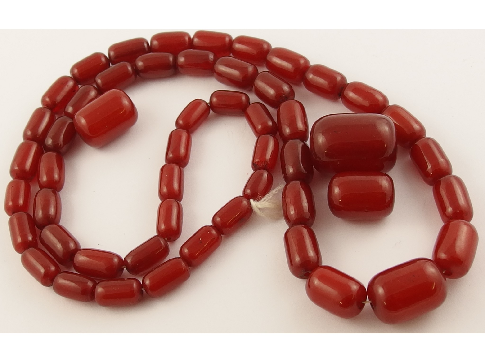 Appraisal: A string of cherry amber coloured beads with three loose