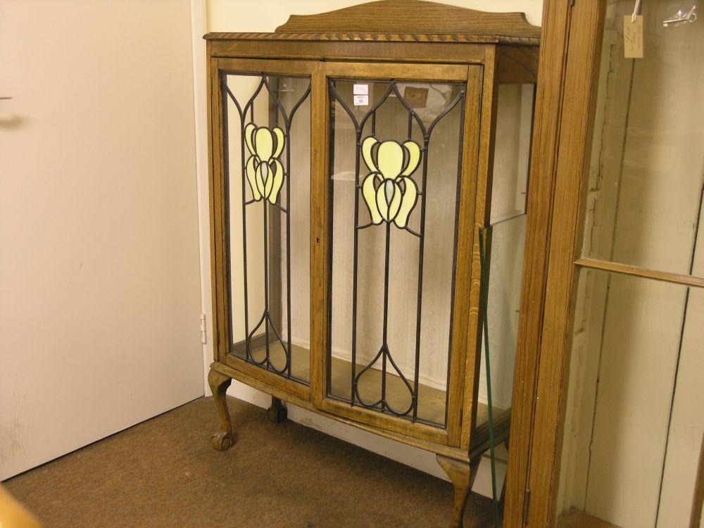 Appraisal: An oak bow fronted display cabinet enclosed by a pair